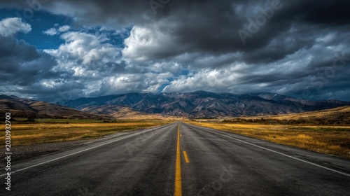 Road leading to mountains under a dramatic sky with moody clouds