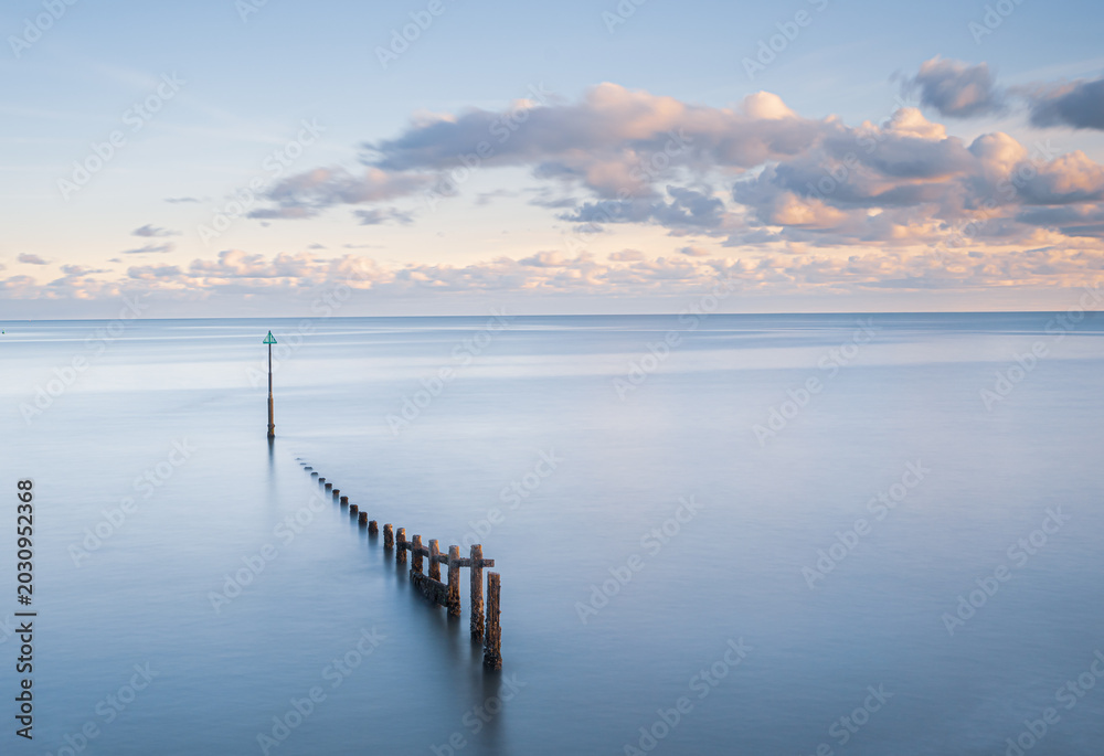 Fototapeta premium Minimalist Long Exposure Seascape with Wooden Posts and Calm pastel Water 