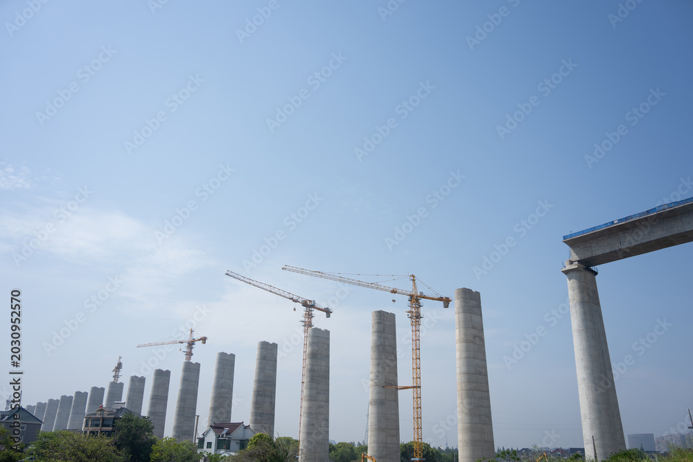 Fototapeta premium Construction site of bridge piers with cranes under blue sky