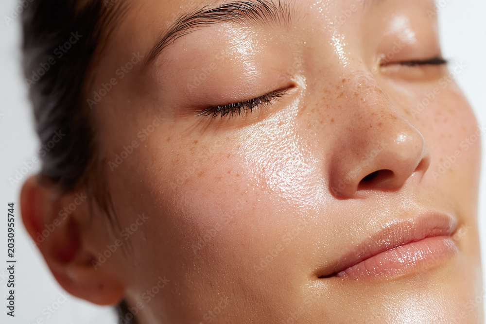 Fototapeta premium Young woman with radiant hydrated skin, closed eyes, dewy complexion, subtle freckles, smooth texture, relaxed expression