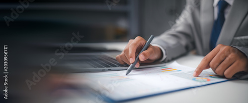 Konstfotografi Businessman analyzing financial graph report and marketing data on clipboard with laptop