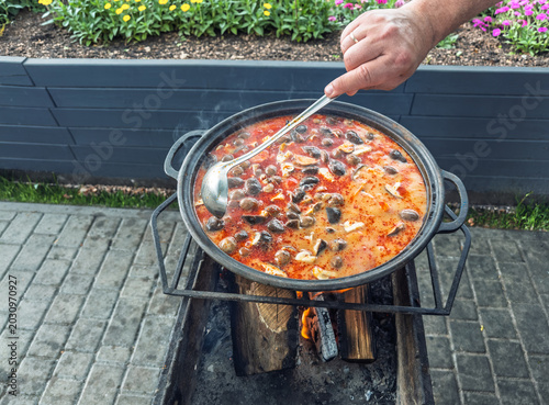 Cuadro en lienzo Cooking spicy Tom Yum soup in a large cast iron kazan over an open wood fire out