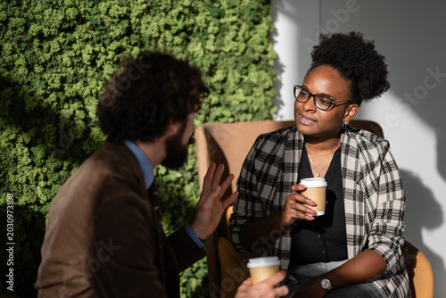 Fotografie Coworkers drinking coffee having a business conversation