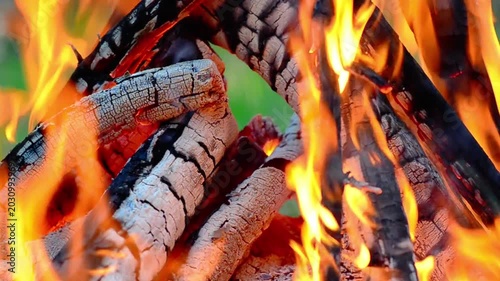 Detailed 4K macro shot of glowing hot charcoal embers and ash in a campfire with intense fire flames, heat distortion, and authentic crackling sound. Static close up. 