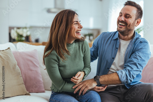 Slika na platnu Happy Couple Laughing Together on Sofa at Home Enjoying Cozy Casual Lifestyle Re