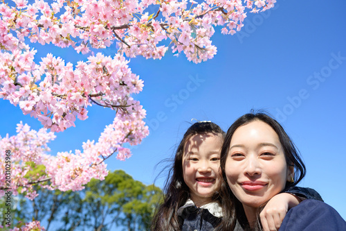 桜の下で笑顔を見せる日本人の母親と娘