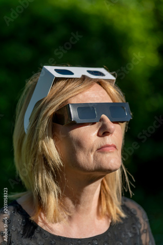 A woman is wearing protective glasses to observe the sun, waiting for the solar eclipse on August 12, 2026