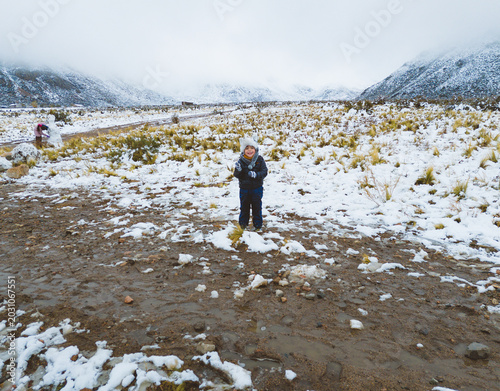child playing in the snow in snowy field