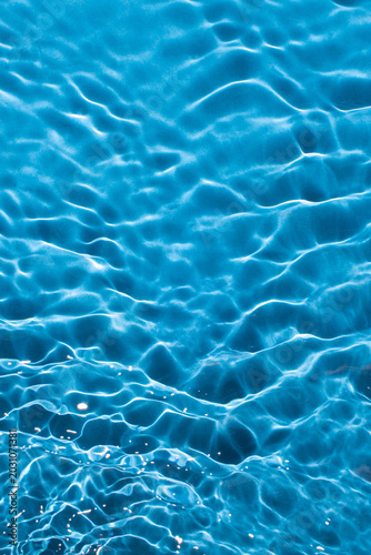 Abstract sparkle water surface with a rippled texture on a light deep blue  background. Abstract summer water background.