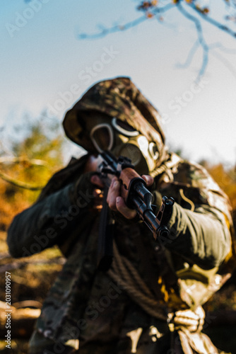 Tableau sur toile Post-apocalyptic survivor or stalker in a gas mask and military camouflage holdi