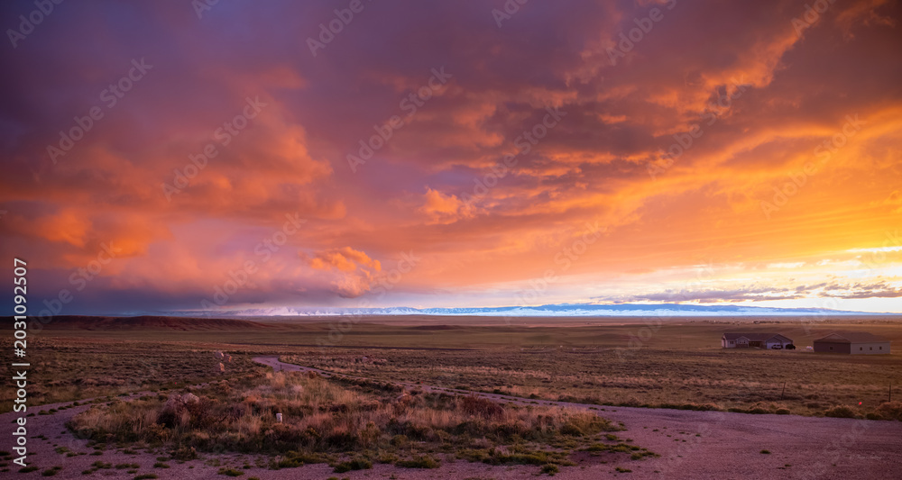 Obraz premium Dramatic orange sunset sky over a vast high plains landscape and mountains, Laramie, Wyoming