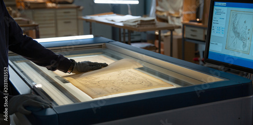 Archivist inspecting historical map on light table with archivist preservation research document antiquities scanning professional cartography restoration historical heritage digitization