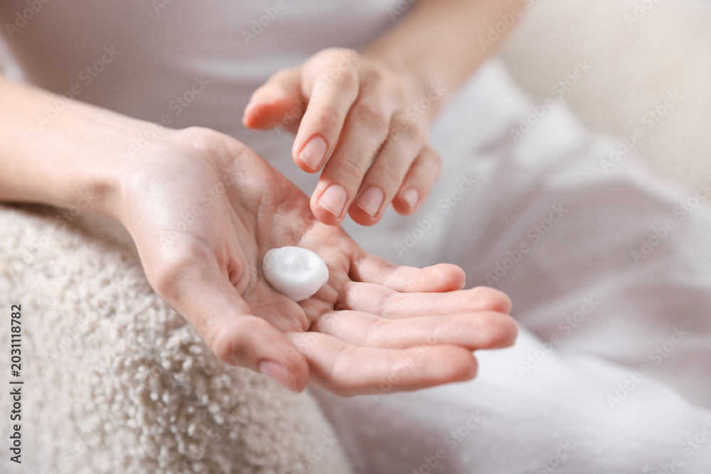 Fototapeta premium Woman applying hand cream at home, closeup