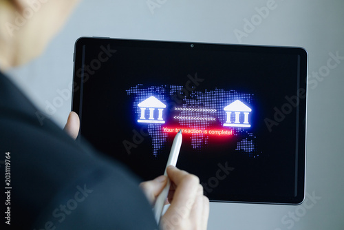 Person using tablet to confirm bank transaction completion while standing indoors