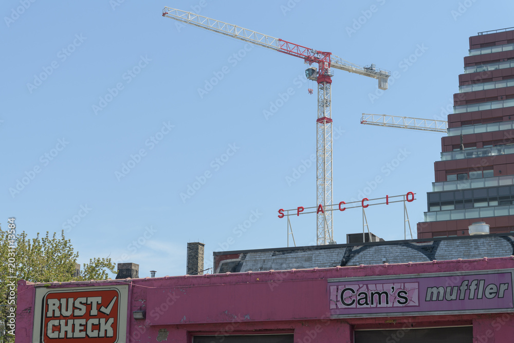 Naklejka premium construction site cranes, rooftop sign of Spaccio, and facade branding of Thruway Muffler / Cam's Auto Service, 475 King St E, Toronto