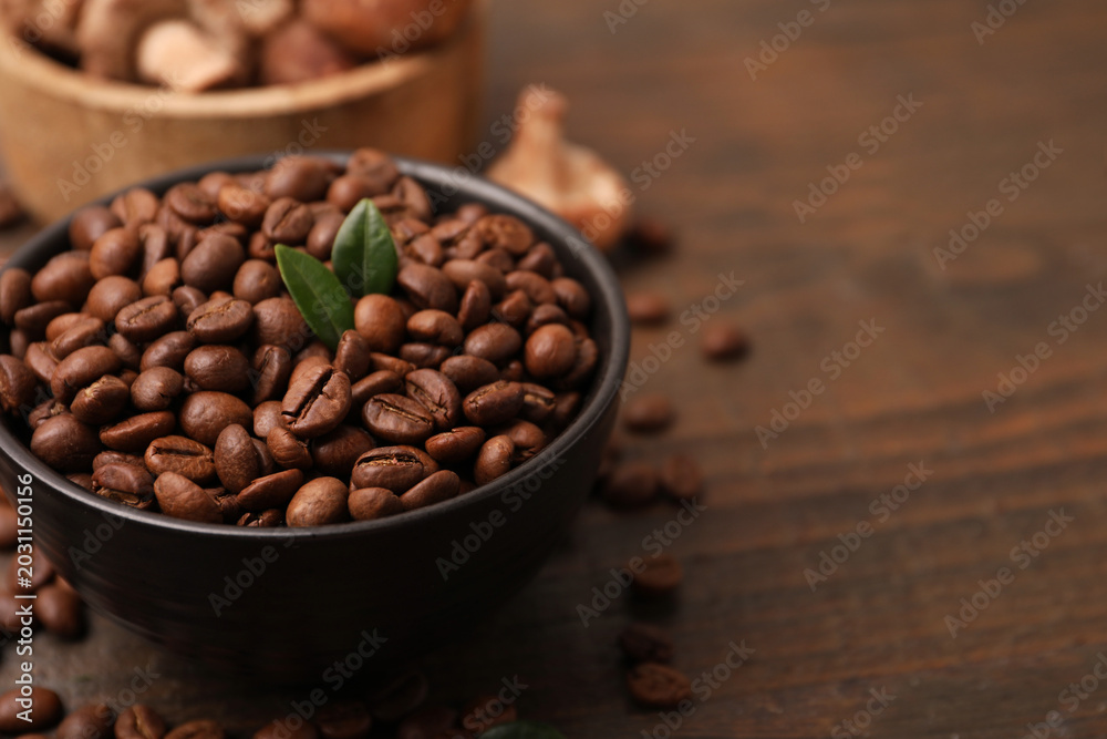 Fototapeta premium Coffee beans and mushrooms on wooden table, closeup. Space for text
