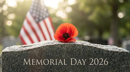 Single vibrant red poppy flower rests atop a grey granite headstone engraved with memorial day 2026 with a softly blurred american flag and green foliage in the background evoking