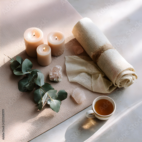 Relaxation setup with candles, tea, and soft textiles on a mat during daylight