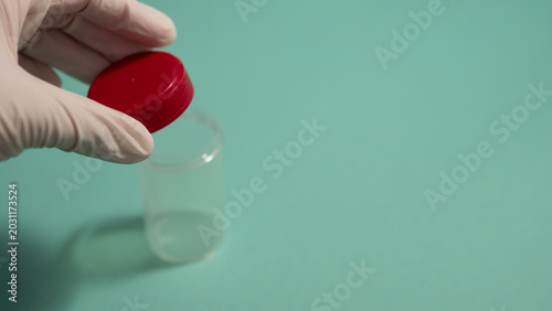 Quadro su tela Gloved Hand Holding Empty Specimen Container with Red Cap — Medical Sample Colle