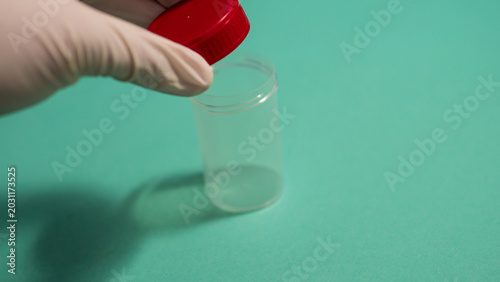 Bild auf Leinwand Gloved Hand Holding Empty Specimen Container with Red Cap — Medical Sample Colle