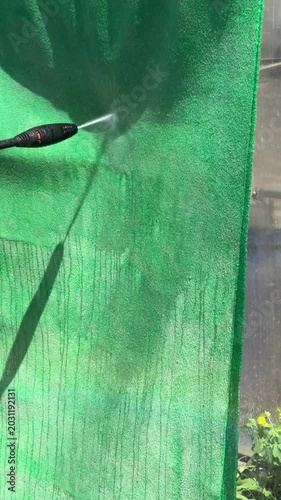 Vertical video still of a pressure washer cleaning a green carpet, perfect for social media, cleaning tips, or product advertising