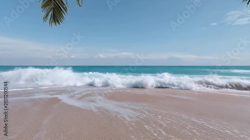 Tropical waves gently lapping sandy beach under clear blue sky