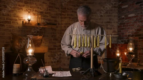 19th century candle maker trimming and dipping a beeswax candle