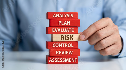 Professional hand carefully extracting 'Risk' block from a strategic business process tower, symbolizing crucial risk management, assessment, and mitigation in corporate planning