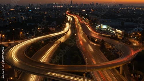 Time-lapse of a busy highway interchange at night with light trails from cars.