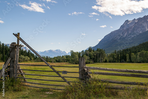 Tableau sur toile Rustic split-rail fence and weathered gate framing a mountain valley meadow in s