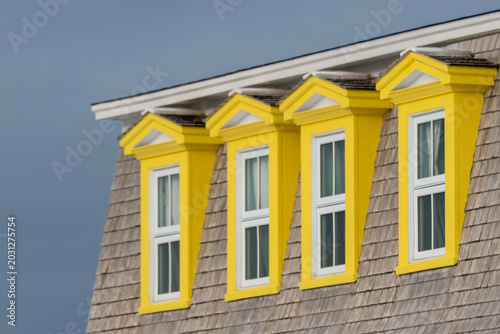 Foto A row of peaked, yellow colored window gable dormers with white frames