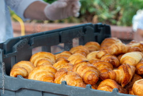 Fotografie A grey plastic bakery tray of French croissants for sale at a market