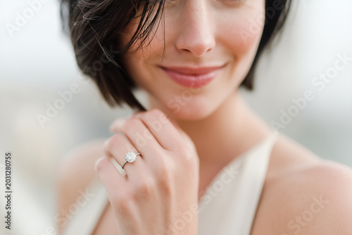 Elegant woman close up hand ring diamond smile beauty fashion jewelry happiness Elegant woman with short dark hair smiling close up of hand displaying diamond ring beauty and happiness fashion