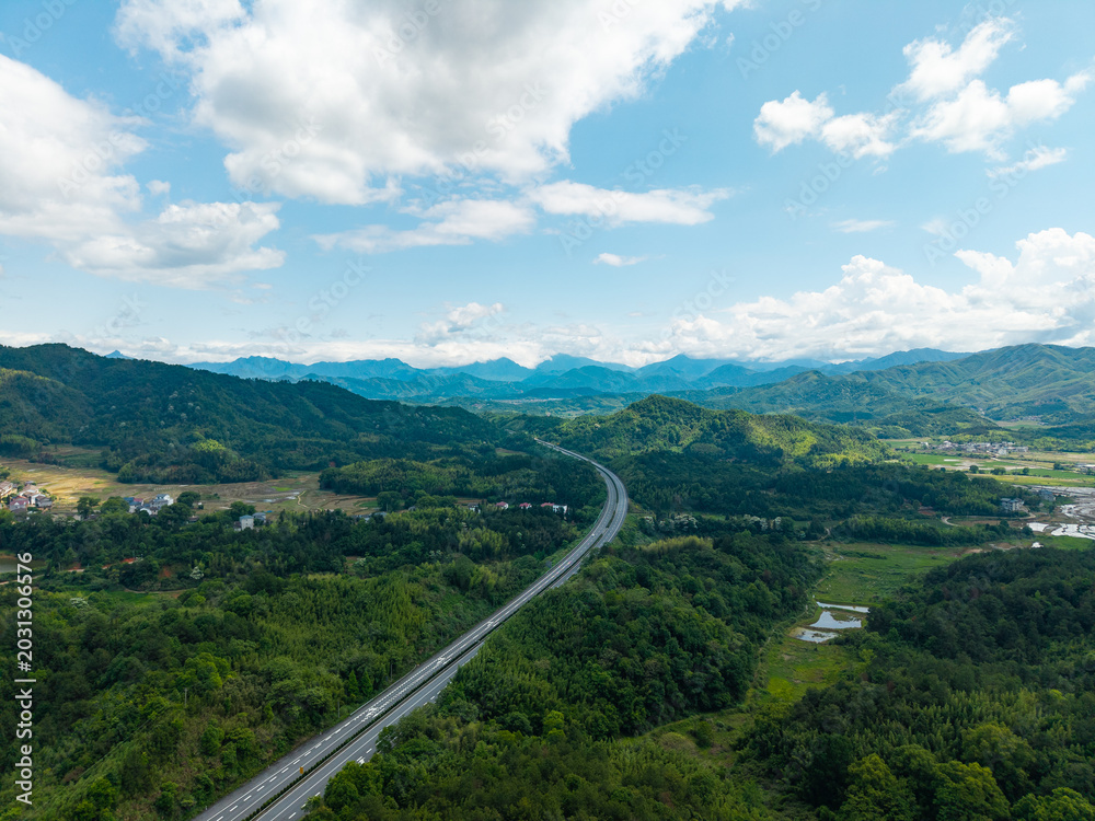 Fototapeta premium A high angle aerial view of a highway stretching through the green mountains and landscape of Wuyi Mountain in Fujian China