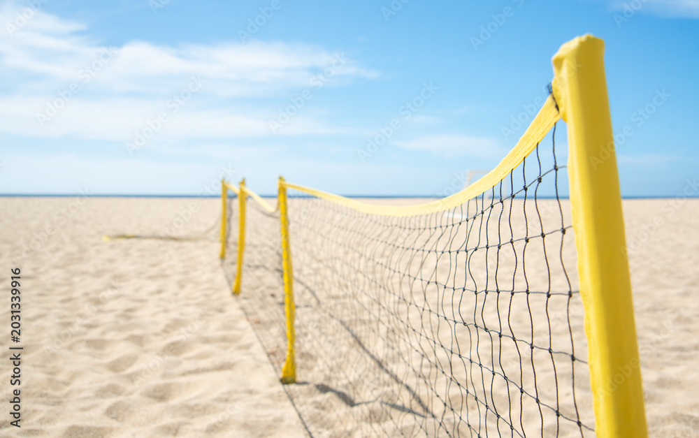Fototapeta premium Close up of Bright Yellow Volleyball Net Stretched on Sandy Beach