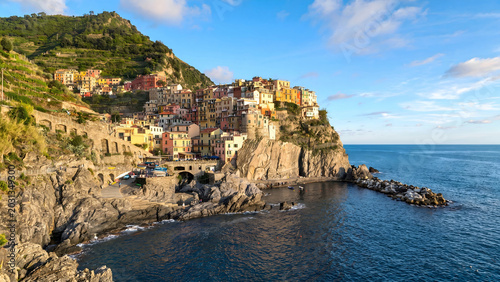 Quadro su tela Colorful Italian village clinging to rocky cliffside overlooking blue sea