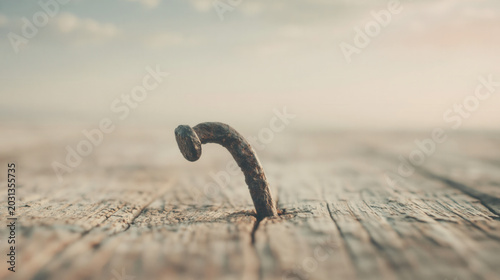 Rusty bent nail protruding from wooden surface minimal concept
