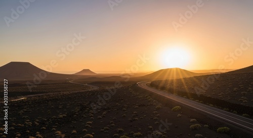 Serene highway carves through desert landscape at sunset, sunburst flares