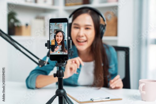 Bild auf Leinwand Selective focus phone in host channel of young beautiful Asian in creative broadcaster talking online explaining to promote marketing or consultant in daily life with listener at studio