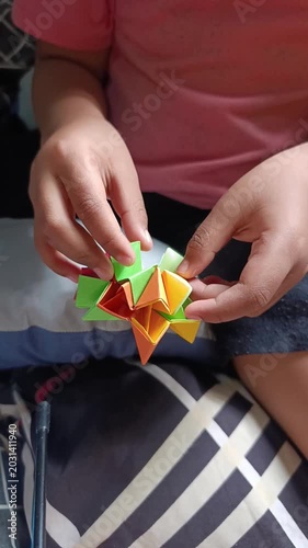 Child Holding Colorful Origami Shapes Crafting in Cozy Indoor Setting