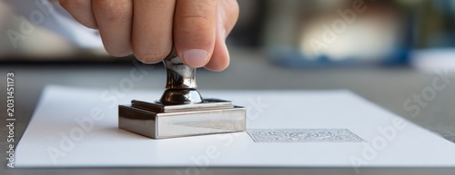 Person using a stamp on a document in an office setting  