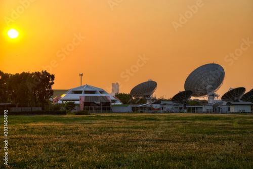 Many big satellite dish antenna stations by meadow at sunset, Bangkok