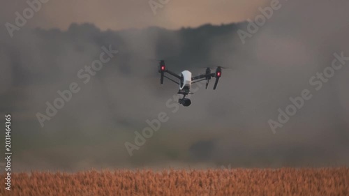 Unmanned aerial vehicle inspects crops at dusk, Autonomous drone surveys wheat fields during evening dusk hours