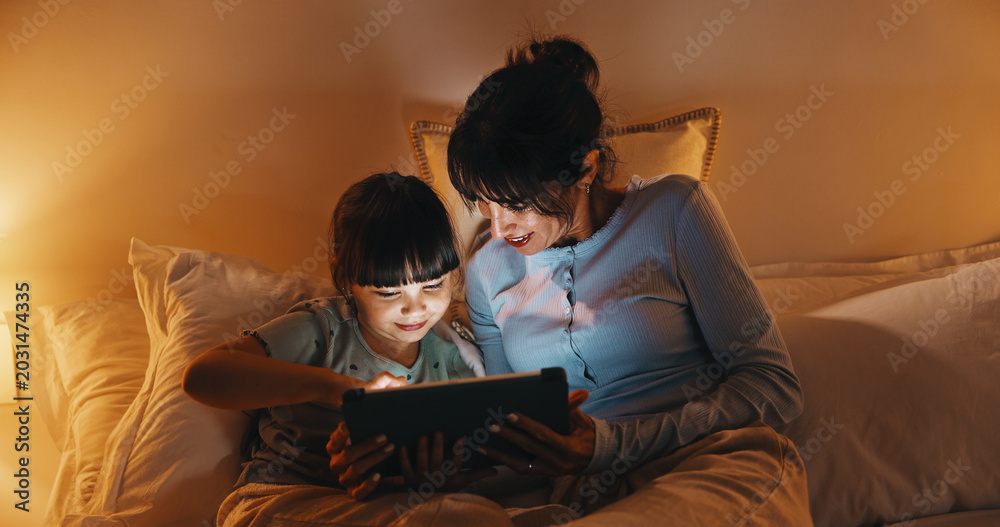 Obraz premium Night, mother and child in bed with tablet, reading ebook and bedtime story for bonding together. Evening, mom and daughter relax in home with tech, literature or kids storytelling app for fairytale.