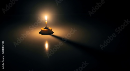 Single lit candle on a small cake in total darkness with long shadow