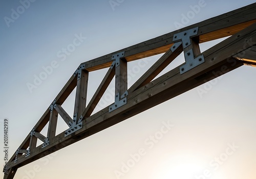 Wooden timber truss structure against a clear sunset sky