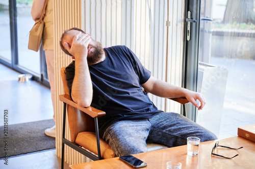 Foto Tired white bearded man covering face and slumping in chair, clear signs of fati