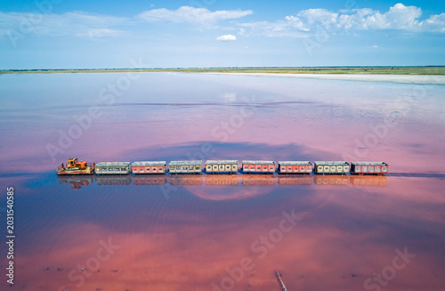 Tableau sur toile Aerial view of an old train rides on the railway laid in the water through the salt lake