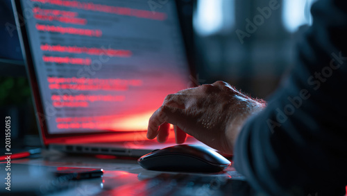 Phishing email on computer screen shows suspicious links as user interacts with mouse at home office during evening hours