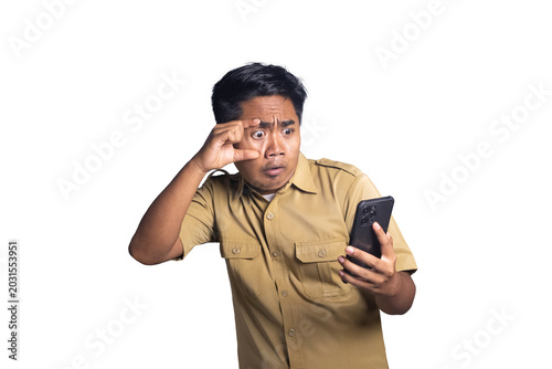 Schilderij op canvas Indonesian civil servant widening eye with fingers in shock while looking at smartphone screen